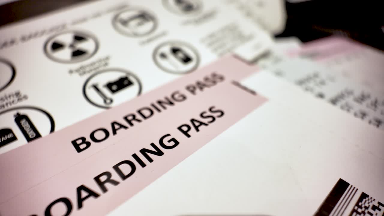 Close up printed boarding pass over prohibited items list informing passengers about dangerous goods before boarding airplane