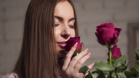 mujer atractiva joven que huele un ramo de rosas