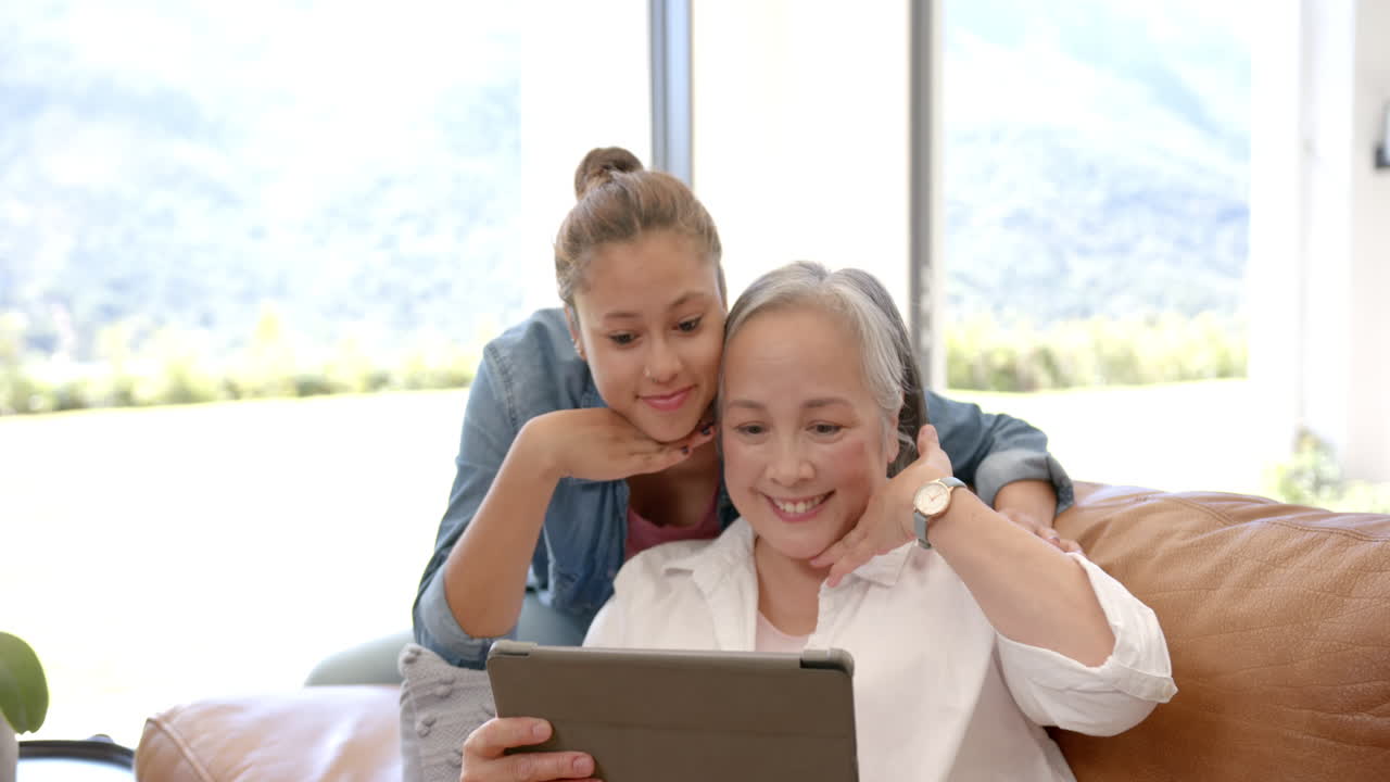 Using tablet together, smiling asian grandmother and granddaughter enjoying quality time at home