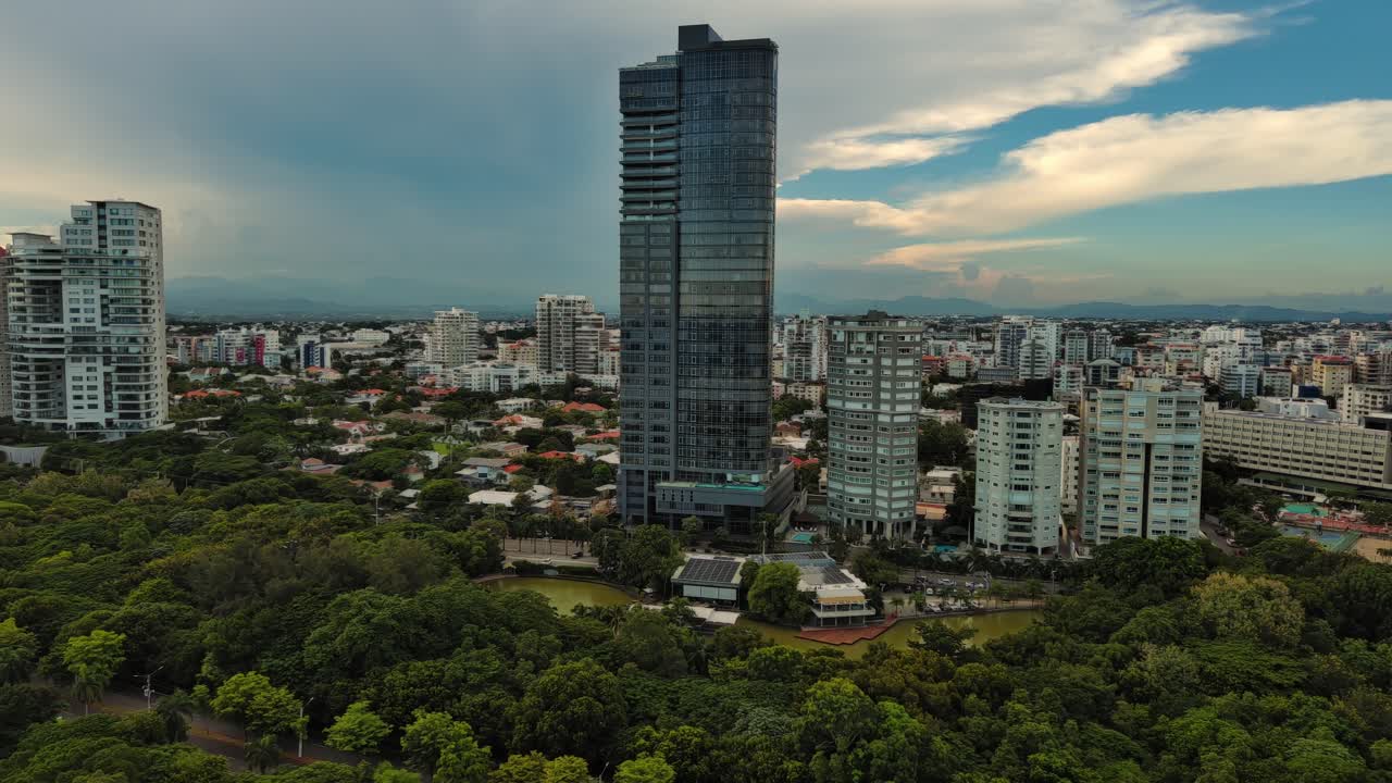 Anacaona 27 tower skyscraper and Enriquillo Lake, Mirador Sur, Santo Domingo cityscape in Dominican Republic. Aerial backward