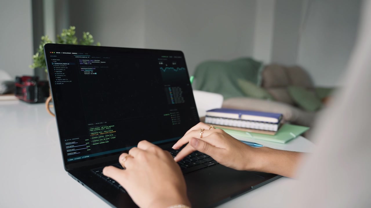Softwareentwickler tippt Code auf dem Laptop im Homeoffice.