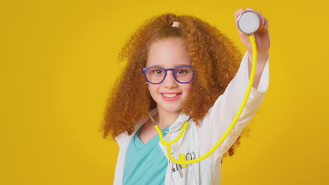 Studio-Portrait-Of-Girl-Dressed-As-Doctor-Or-Surgeon-With-Stethoscope-Against-Yellow-Background