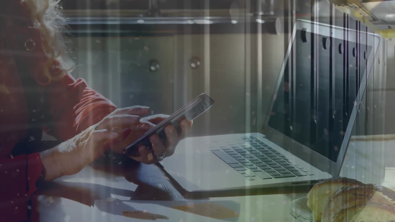 This video features a middle-aged woman using a laptop and mobile phone in her kitchen at home