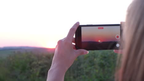 person recording sunset with a smartphone