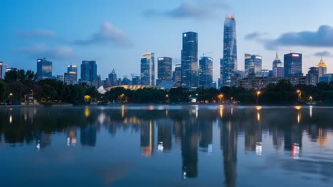 a serene urban landscape at dusk: reflections of modern skyscrapers and soft clouds over a calm lake create a tranquil atmosphere in the evening sky