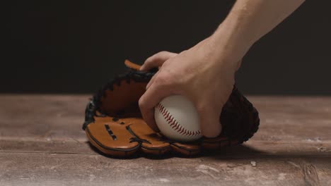 Baseball-Stillleben-Mit-Person,-Die-Den-Ball-Aufhebt,-Und-Fängerhandschuh-Auf-Holzboden