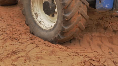 close up of big tractor wheel driving on soft sand ground