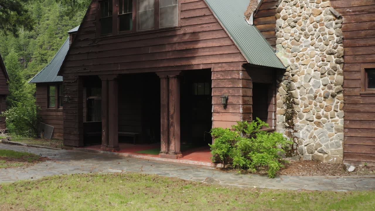 Flying towards entrance of old wooden cabin in wilderness forest of America