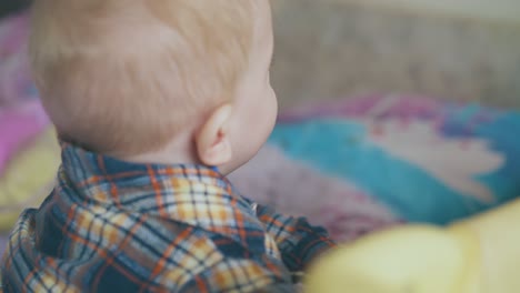 un bebé gracioso de ojos azules juega con alambre en el patio de recreo