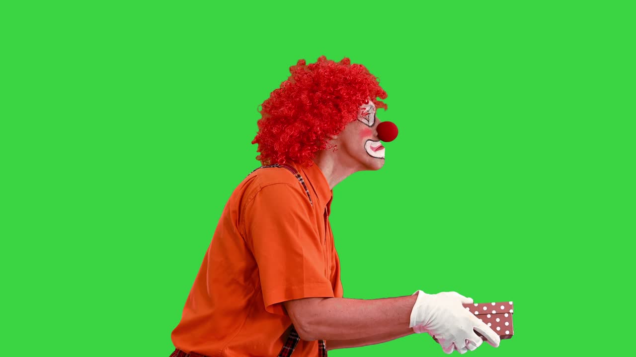 payaso llevando una caja de regalos y mirando dentro de ella en una pantalla verde, llave de croma