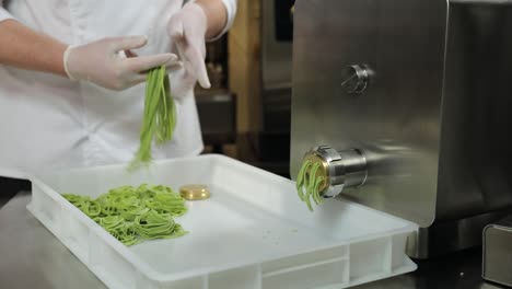 chef making green pasta with machine