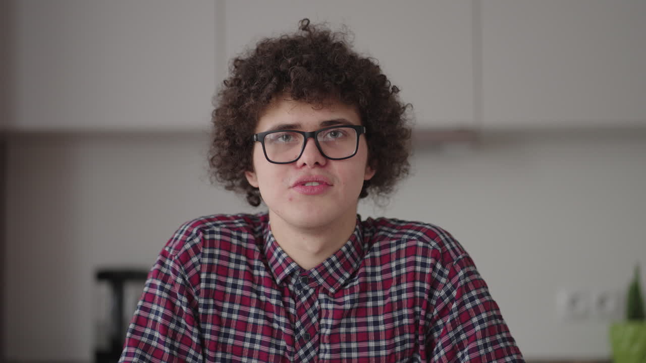 un hombre con gafas mirando a la cámara habla