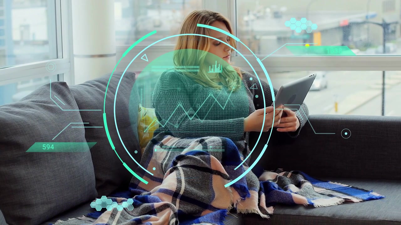Woman tapping tablet and adjusting blanket while animated turquoise HUD revealing finance charts