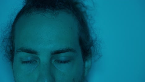 moody portrait of a worried man with blue lighting, showing his contemplative gaze as eyes swing side to side