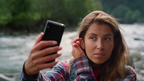 excursionista arreglando el cabello antes del chat de video en el teléfono inteligente. chica agitando la mano a la cámara