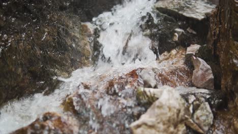 Zeitlupe-Nahaufnahme-Von-Wasser,-Das-über-Felsen-Läuft---Boom-Shot