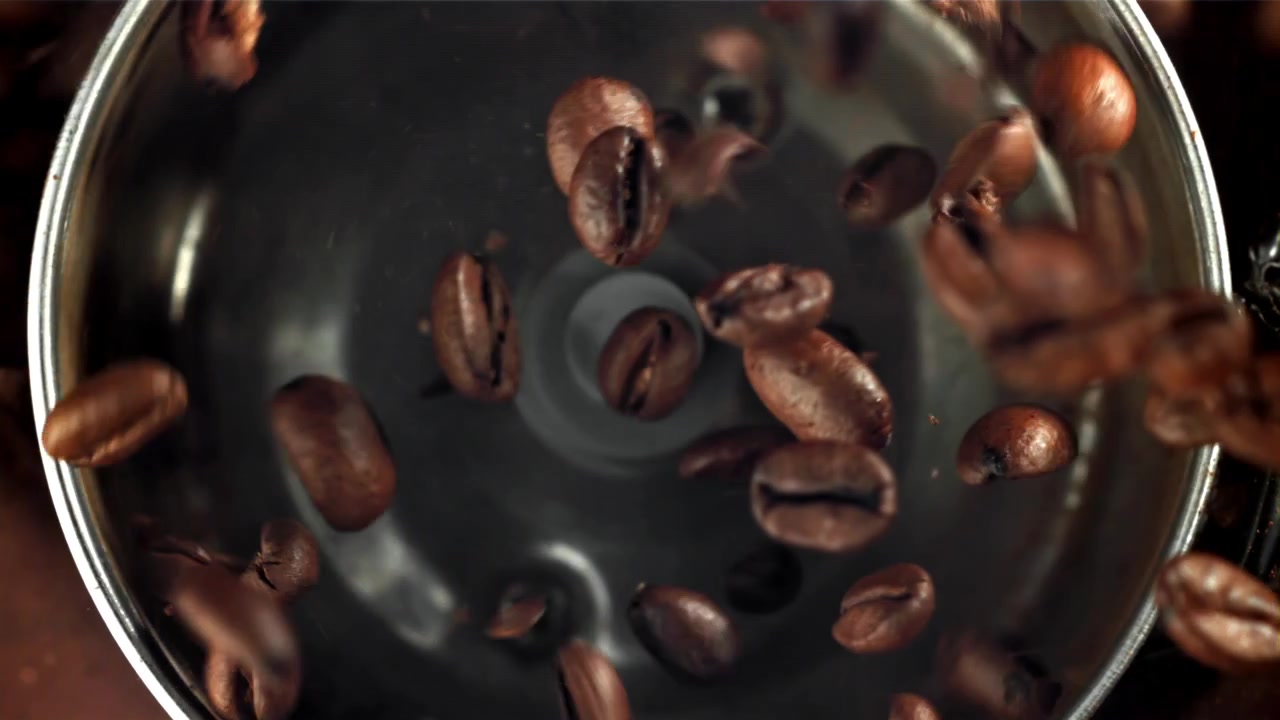 Chicchi di caffè tostati che cadono in un macinacaffè al rallentatore