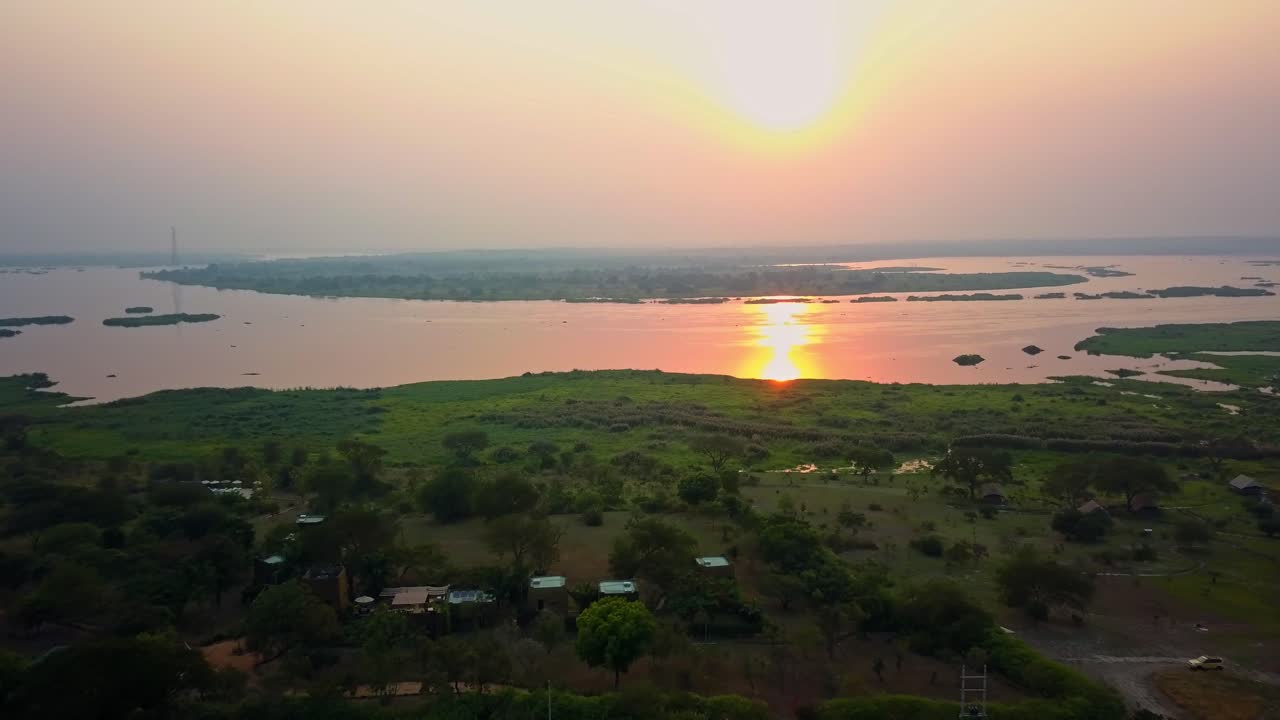 Early morning aerial drone view as the sun rises above the meandering Victoria Nile, reflecting intense golden light over green wetlands and bush near Pakwach, west Nile sub-region, northern Uganda