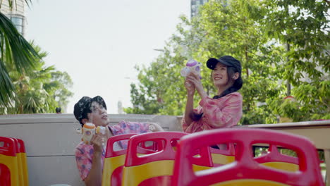 asiatic young couple playing together with soap bubble using a toy gun while travelling on a bus