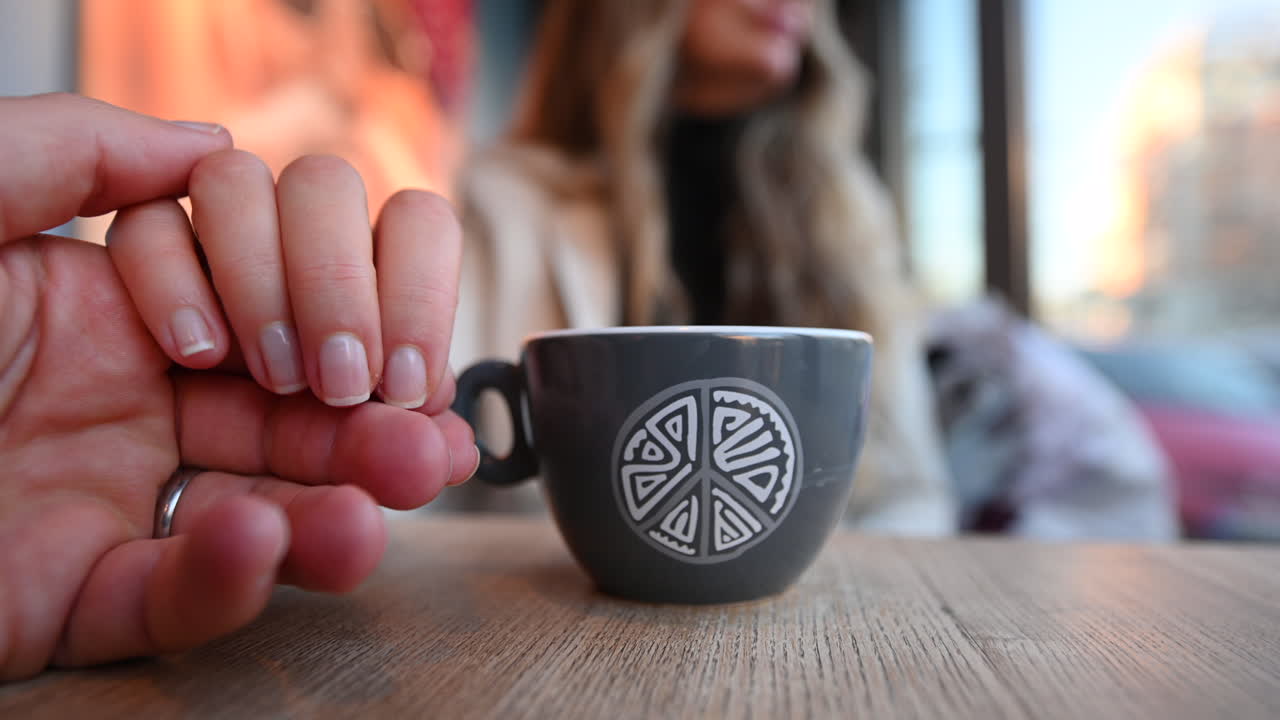 Couple holding hands at a restaurant, coffee cup on table