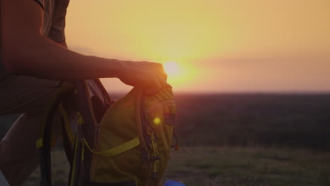 A-Man-Is-Packing-His-Backpack-At-Sunset-Preparing-For-A-Trip-Or-Trekking-4k-10-Bit-Video