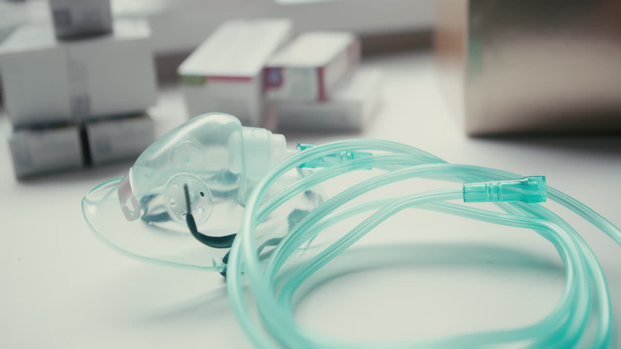 Attrezzatura respiratoria a riposo, inclusa una maschera per l'ossigeno verde e tubi arrotolati, vicino a scatole di medicinali. Configurazione per l'assistenza sanitaria domiciliare per malattie croniche.