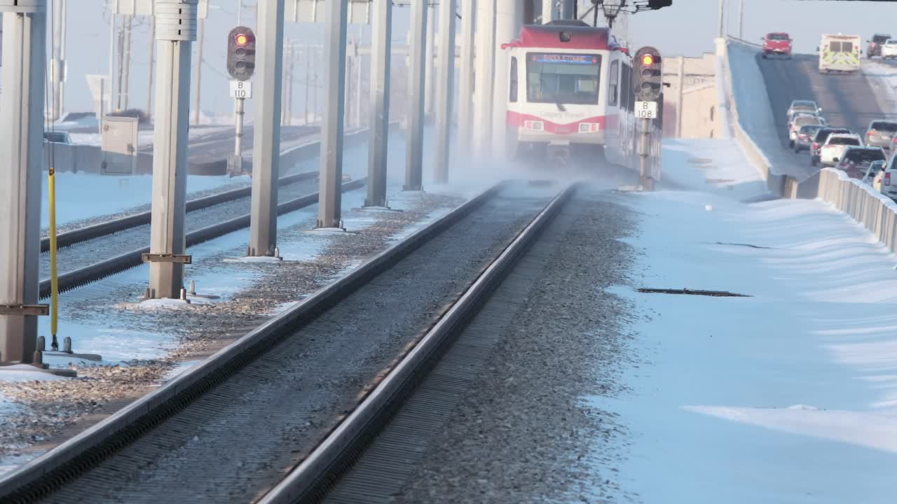 Calgary Transit train rolls down ice cold tracks, kicking up snow