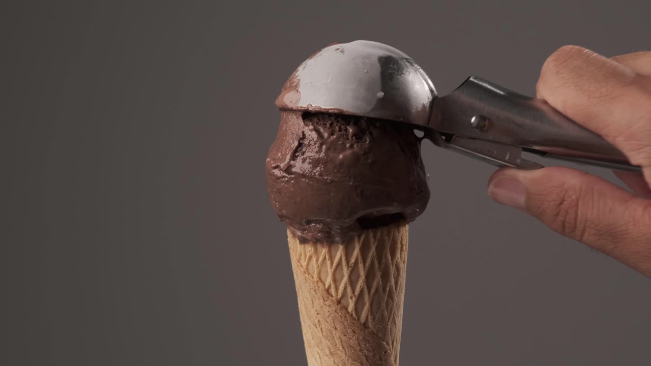 Una persona che serve delizioso gelato al cioccolato in un cono waffle. Concetto di dolce e zucchero
