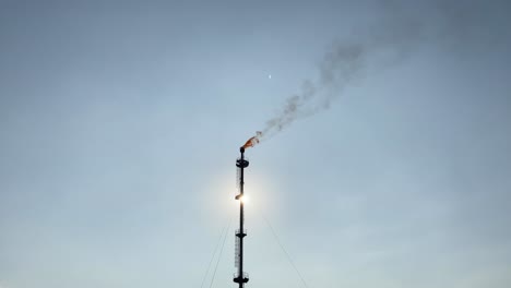 Silhouette-or-heavily-backlit-view-of-oil-refiner-smoke-stack-flare