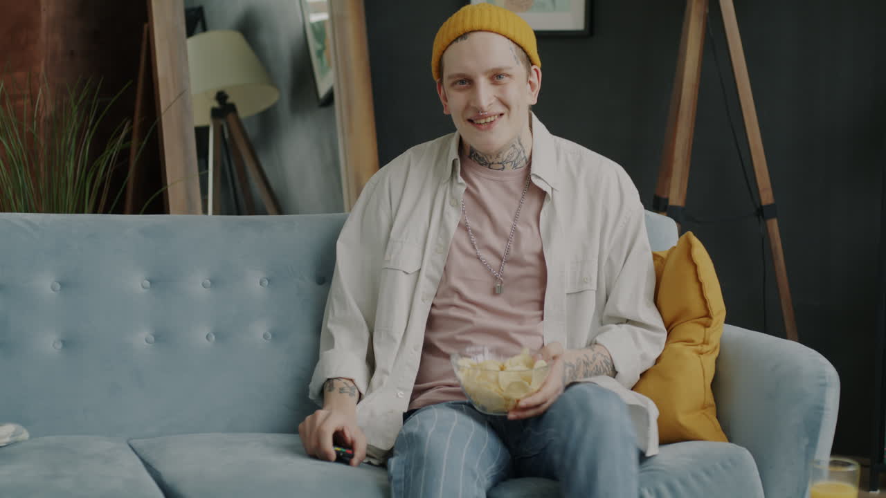Young Man Relaxing on Couch and Eating Chips
