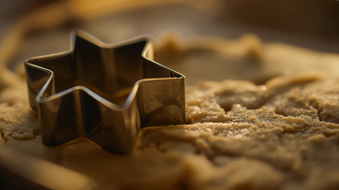 Opening shot initiating focus shifting on star cookie cutter in tray, revealing crystals on dough