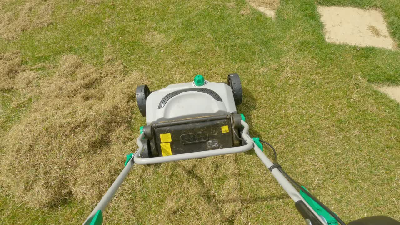 POINT OF VIEW: Gardener using grass aerator while taking care of backyard lawn