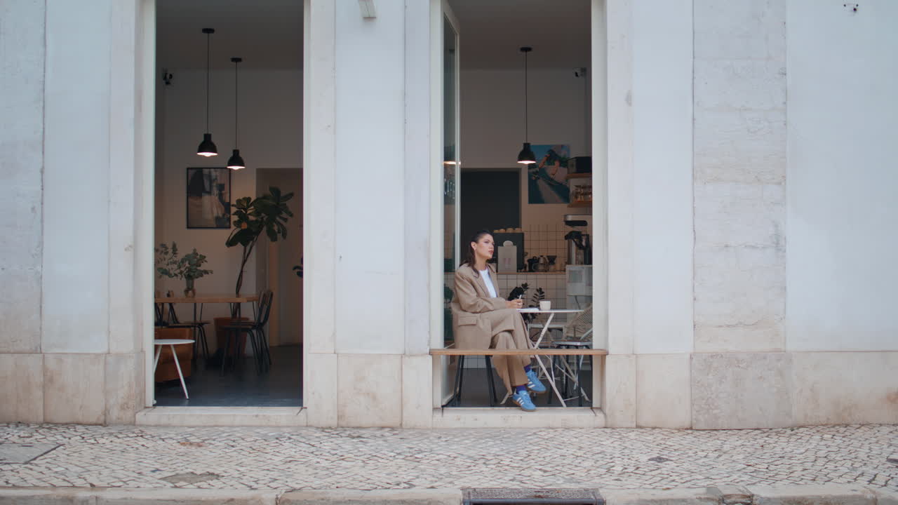 거리 식당에서 쉬고 있는 여자가 작은 테이블에 혼자 앉아 있다.