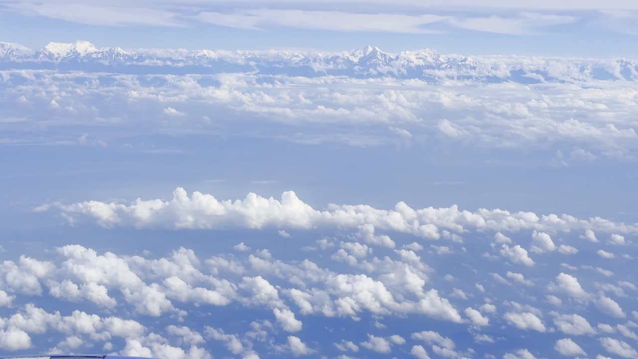 Footage showing clouds in the sky as seen from an airplane window, capturing aerial atmospheric views, soft white formations, and a serene blue horizon, ideal for travel, aviation, and nature visuals