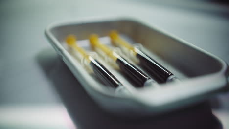 syringes with a dark liquid on a medical tray