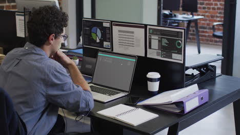 hombre caucásico sentado en el escritorio codificando datos en una computadora portátil