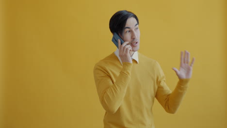 man talking on a phone in a yellow studio setting