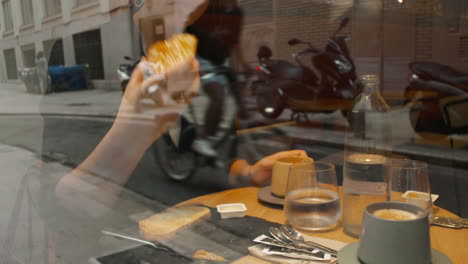 woman eating at a table in a cafe - through the glass