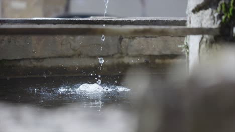 clean water droplets falling into stone fountain at historical courtyard in slow motion.