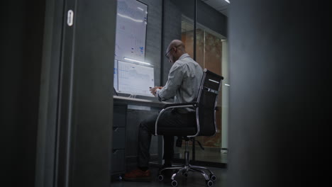 happy stock trader monitoring real-time stocks on computer, having phone call, celebrating winning trading deal. excited african american investment agent making profitable investments. vertical shot.