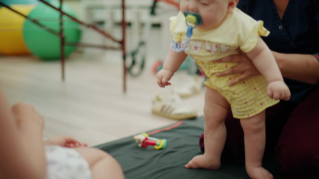 Profissional de saúde auxiliando um bebê durante um exercício, apoiando o desenvolvimento e a reabilitação na primeira infância.
