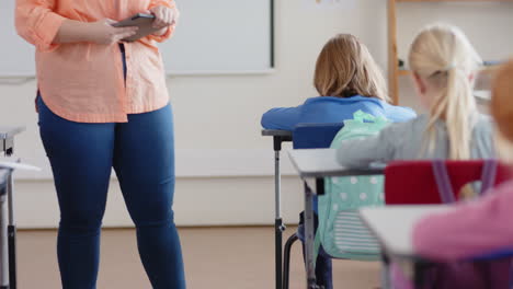 in school, female teacher using tablet while assisting student in classroom