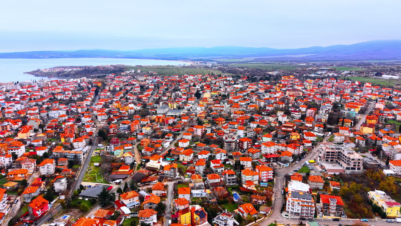 Tiheästi asuttu rannikkokaupungin alue oranssitiilikatoilla ja vihreillä kukkuloilla. Korkealta kuvattu ilmakuva pienestä Bulgarian vanhastakaupungista.