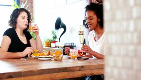 pareja de lesbianas interactuando entre sí mientras desayunan