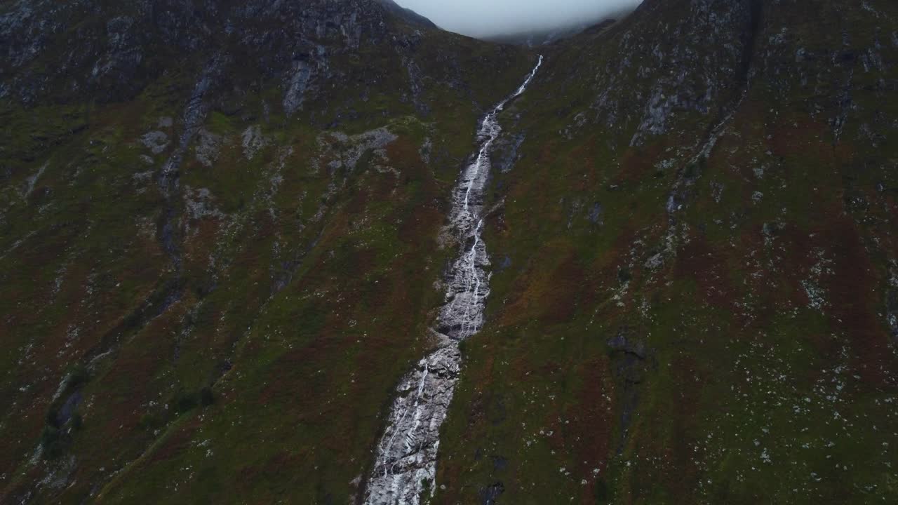 paisaje en cámara lenta de drones de la cascada de ben nevis formación geológica corriente de agua cae a través de la montaña húmeda húmeda