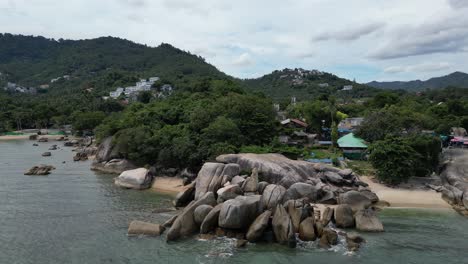 right to left pan shot of rocky beaches and lush green trees in the background