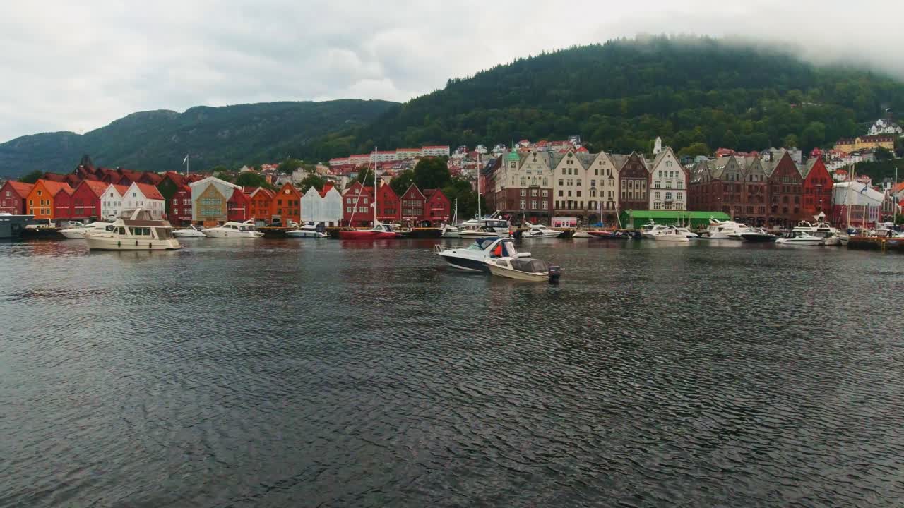 Boat Trip Leaving Bergen City Harbour with Bryggen Hansa Quarter Historical Architecture Along the Waterfront with Scenic Hillside in the Background, Norway.