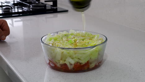 close-up of fresh cabbage and tomato salad in a glass bowl as olive oil is being poured on top, highlighting healthy eating and freshness