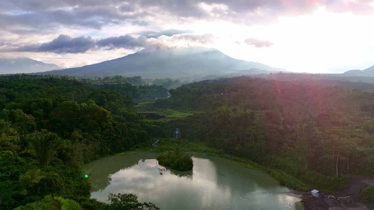 Picturesque lake with mountain background in the middle of green forest in sunny morning, Merapi volcano, Indonesia.