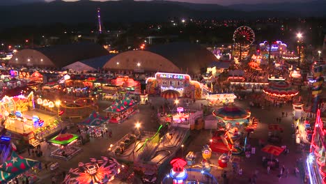 a high angle view over a brightly lit amusement park with many rides and attractions 1